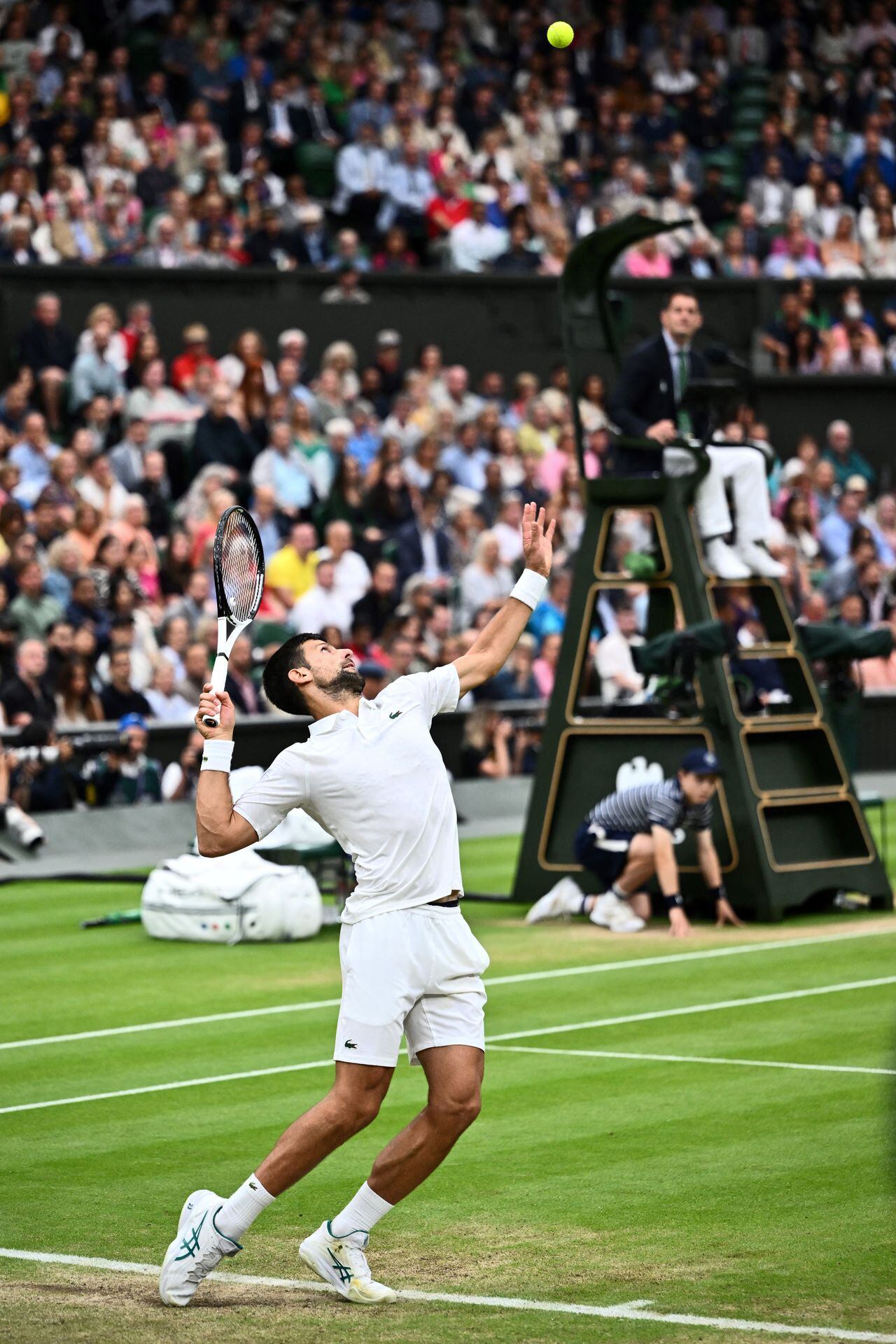 Serbia's Novak Djokovic serves the ball to Italy's Jannik Sinner during their men's singles semi-finals tennis match on the twelfth day of the 2023 Wimbledon Championships at The All England Lawn Tennis Club in Wimbledon, southwest London, on July 14, 2023. (Photo by SEBASTIEN BOZON / AFP) / RESTRICTED TO EDITORIAL USE