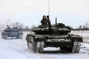 En esta foto distribuida por el Servicio de Prensa del Ministerio de Defensa ruso el 14 de febrero de 2022, tanques recorren un campo durante maniobras militares en la región de Leningrado, Rusia.