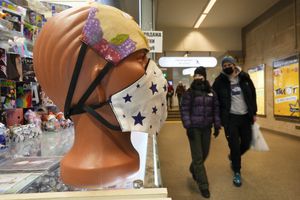 People walk past face masks displayed for sale in St. Petersburg, Russia, Monday, Jan. 24, 2022. Daily new coronavirus infections in Russia have reached an all-time high and authorities are blaming the highly contagious omicron variant, which they expect to soon dominate the country's outbreak. (AP Photo/Dmitri Lovetsky)