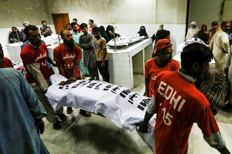 Los rescatistas mueven el cuerpo de una víctima, que murió junto con otros en una estampida durante la distribución de comida. La fotografía tiene lugar en la morgue de un hospital en Karachi, Pakistán
