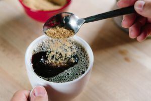 Azúcar moreno que se vierte en una taza de café, un alto ángulo de visualización