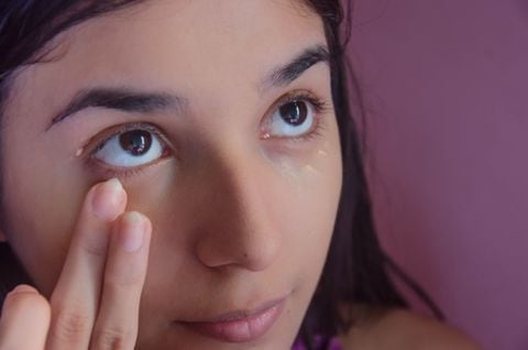 Young woman blending concealer under her eyes. Close up.