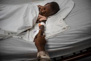 Rickson Beaubrun, quien resultó herido por una bala perdida mientras dormía en su cama en Cite Soleil, sostiene la mano de su hermana mientras se recupera en una clínica administrada por Médicos Sin Fronteras en el barrio Tabarre de Port-au-Prince, Haití, el jueves 11 de noviembre. 3 de enero de 2022. 