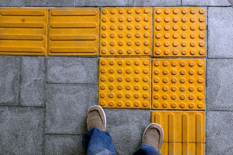 Pedestrian walking on tactile paving on footpath