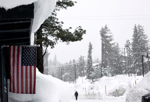 MAMMOTH LAKES, CALIFORNIA - 10 DE MARZO: Una bandera estadounidense cuelga frente a un negocio mientras la nieve cae sobre los bancos de nieve acumulados de tormentas anteriores durante otra tormenta de invierno en las montañas de Sierra Nevada el 10 de marzo de 2023 en Mammoth Lakes, California. Las montañas de Sierra Nevada de California están siendo golpeadas por fuertes nevadas en elevaciones más altas, lo que eleva aún más los niveles de la enorme capa de nieve. Las comunidades de las montañas que aún se están recuperando de tormentas anteriores en elevaciones más bajas se enfrentan a posibles inundaciones debido a la escorrentía de lluvia de la décima tormenta fluvial atmosférica del estado. El presidente Joe Biden aprobó la solicitud de emergencia presidencial del gobernador Gavin Newsom en respuesta a las recientes tormentas que afectaron a California. Mario Tama/Getty Images/AFP (Foto de MARIO TAMA/GETTY IMAGES NORTH AMERICA/Getty Images vía AFP)