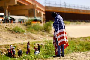 Un migrante de Venezuela, que fue expulsado de los EE. UU. y enviado de regreso a México bajo el Título 42, lleva una bandera de los EE. UU. a orillas del río Bravo, en Ciudad Juárez, México, el 26 de octubre de 2022. 