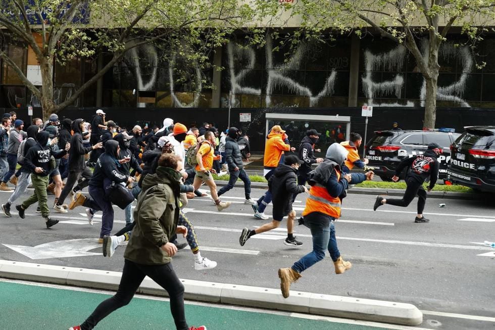 Los manifestantes persiguen a la policía durante una protesta contra la obligación de las vacunas contra el coronavirus en Melbourne, Australia, el 21 de septiembre de 2021. (STR / AFP).