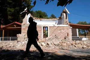 Un vecino pasa junto a una capilla ortodoxa griega dañada por un fuerte sismo en el poblado de  Arcalochori, en la isla sureña de Creta, Grecia, el lunes 27 de septiembre de 2021. (AP Foto/Harry Nikos)