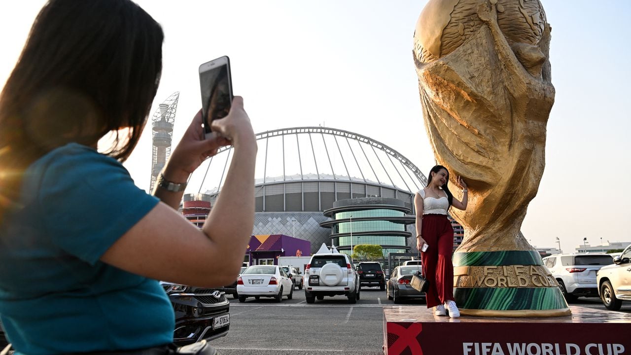 A woman poses in front of the Khalifa Stadium in Doha on November 6, 2022, ahead of the Qatar 2022 FIFA World Cup football tournament. (Photo by Kirill KUDRYAVTSEV / AFP)