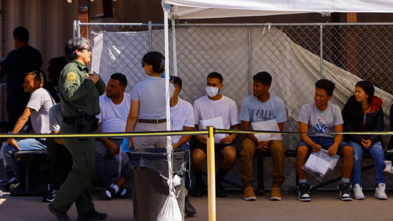 Migrantes que ingresaron ilegalmente a los Estados Unidos y estaban en las calles de El Paso, esperan mientras se entregan voluntariamente en una estación de la Patrulla Fronteriza.