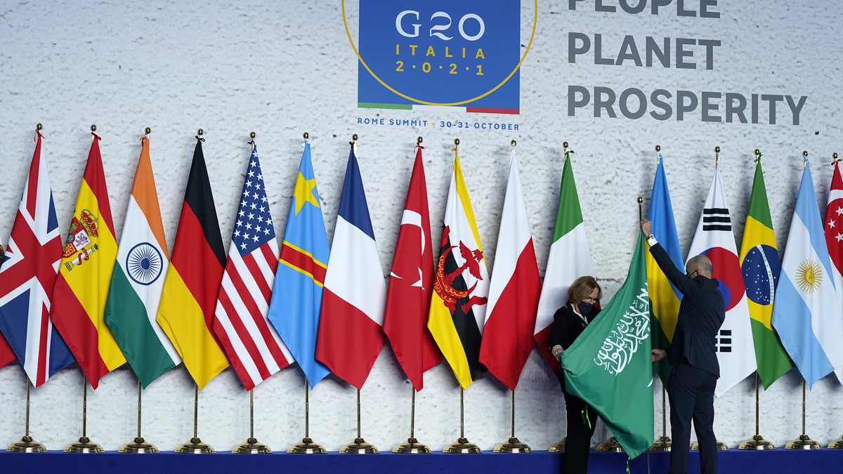 Operarios ajustan la bandera de Arabia Saudí antes de una foto grupal al inicio de la cumbre del G20 en Roma, el 30 de octubre de 2021. (AP Foto/Evan Vucci, Pool)