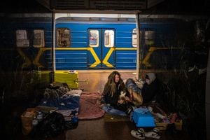 A woman hugs her cat inside a subway wagon in a underground metro station used as a bomb shelter in Kyiv on March 8, 2022. - Ukraine's President Volodymyr Zelensky, invoking the wartime defiance of British prime minister Winston Churchill, vows to "fight to the end" in a historic virtual speech to UK lawmakers. (Photo by Dimitar DILKOFF / STF / AFP)