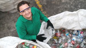Retrato de una mujer que trabaja en un centro de reciclaje clasificando algunas botellas y mirando a la cámara sonriendo - conceptos ambientales