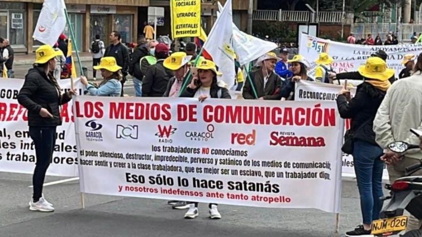 Manifestantes sostienen cartel en contra de varios medios de comunicación.