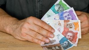 manos de hombre y mujer intercambiando billetes colombianos con fondo blanco
