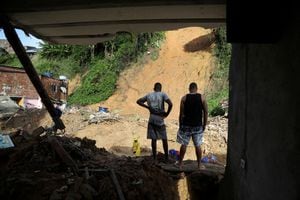 Los hombres se paran sobre los escombros de una casa que se derrumbó durante un deslizamiento de tierra causado por fuertes lluvias en Jardim Monte Verde, en el barrio de Ibura, en Recife, Brasil, 30 de mayo de 2022. Foto REUTERS/Diego Nigro