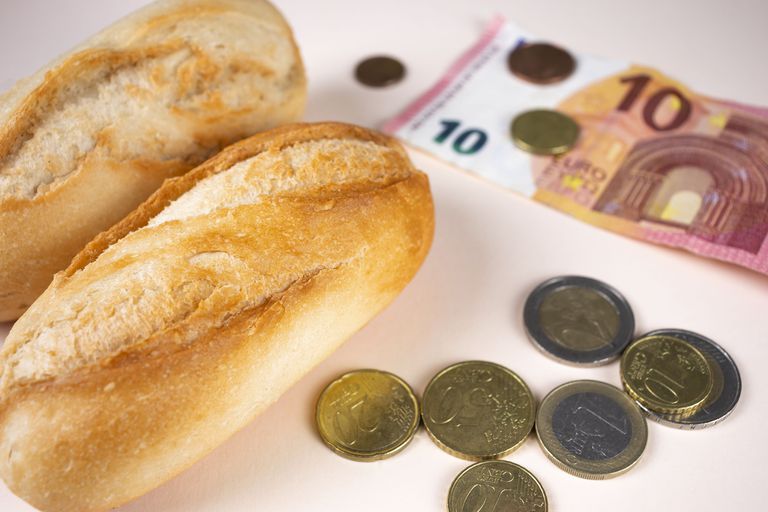 Precio del pan, pan blanco con dinero y monedas en euros. Alimentos caros por inflación, subida de precios y crisis alimentaria