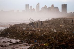 La gente busca artículos que puedan salvar en la playa después de que las fuertes lluvias causaran inundaciones, en Durban, Sudáfrica, el 12 de abril de 2022. Foto REUTERS/Rogan Ward 