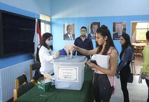Una mujer siria deposita su voto en un colegio electoral de Damasco el 26 de mayo de 2021, cuando comenzó la votación en toda Siria para unas elecciones que garantizan el regreso del presidente Bashar al-Assad para un cuarto mandato/AFP/LOUAI BESHARA