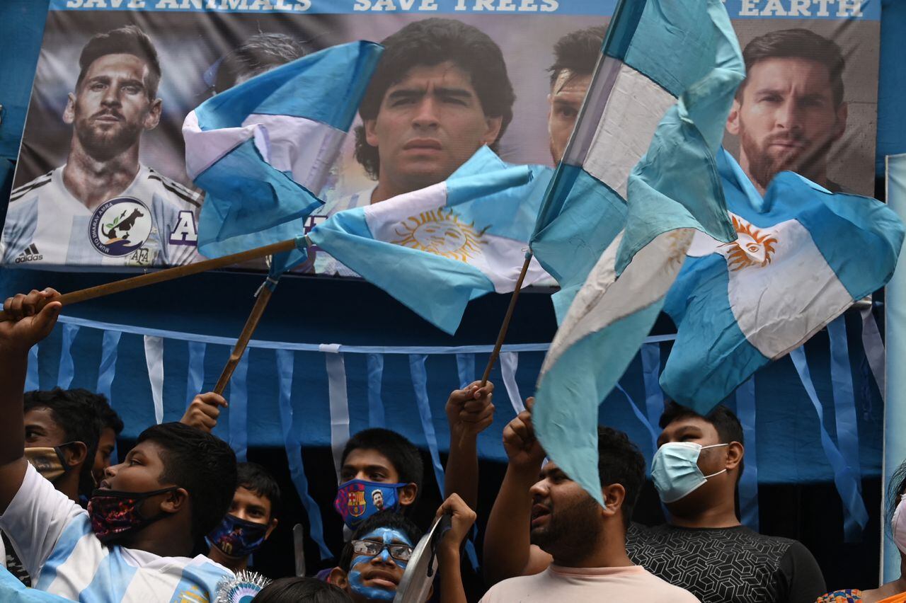 Fans of Argentina hold national flags as they celebrate after winning the Conmebol 2021 Copa America football tournament final match against Brazil, in Kolkata on July 11, 2021. (Photo by DIBYANGSHU SARKAR / AFP)