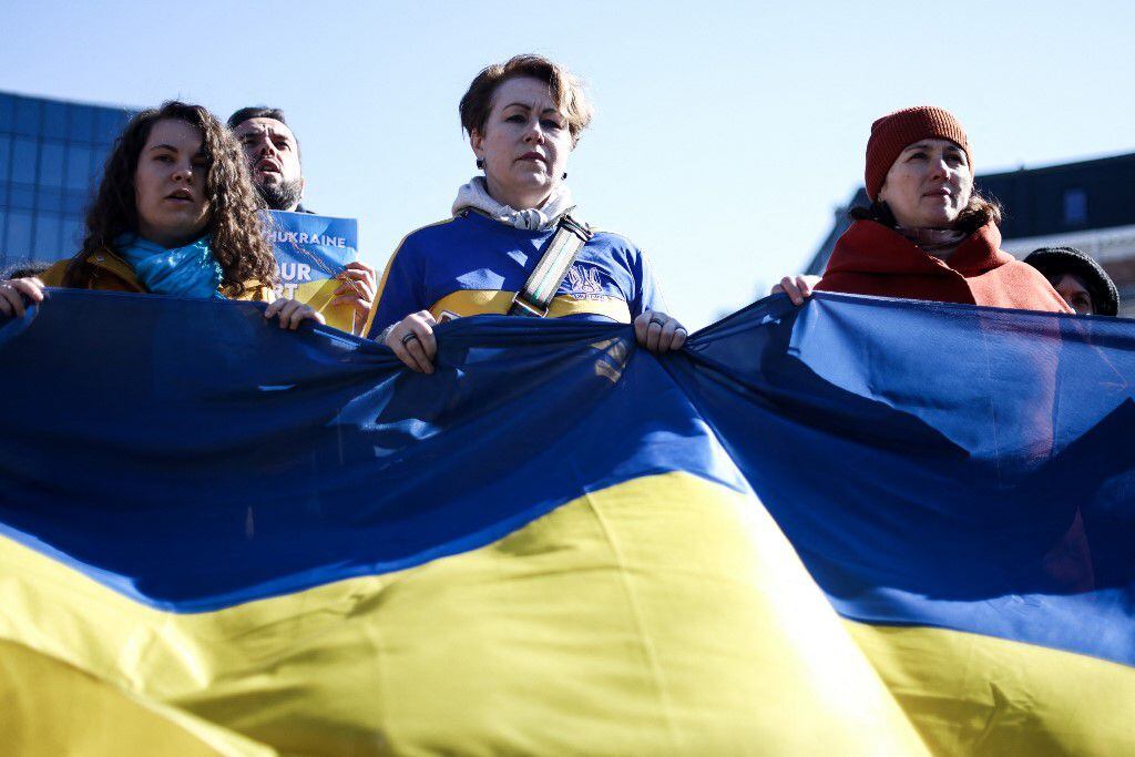 Las mujeres sostienen una bandera ucraniana cerca de las instituciones europeas durante una manifestación llamada "Las mujeres están con Ucrania" contra la operación militar de Rusia en Ucrania como parte del Día Internacional de la Mujer en Bruselas, el 8 de marzo de 2022.
Kenzo TRIBOUILLARD / AFP
