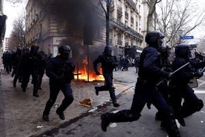 La policía antidisturbios francesa pasa por un incendio durante los enfrentamientos en una manifestación como parte del décimo día de huelgas y protestas nacionales contra la reforma de las pensiones del gobierno francés, en París, Francia, el 28 de marzo de 2023. 