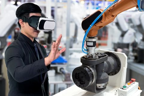 Tecnología de realidad virtual en la industria 4.0. Traje de hombre de negocios con gafas VR para ver el servicio AR, motor de monitoreo térmico para verificar, destruir parte de la máquina de brazo de robot inteligente en fábrica inteligente.