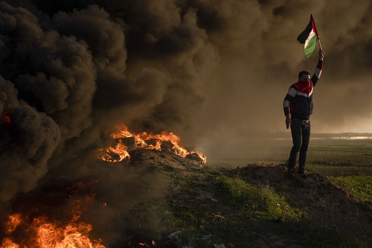 Palestinos queman neumáticos y ondean la bandera nacional durante una protesta contra un operativo militar israelí en Yenín, Cisjordania, el jueves 26 de enero de 2023, en la Ciudad de Gaza. (AP Foto/Fatima Shbair)