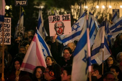 manifestantes sostienen carteles y banderas durante una manifestación contra el primer ministro israelí Benjamin Netanyahu y el gobierno israelí el 27 de enero de 2024 en Tel Aviv, Israel. Según Israel, Hamás todavía mantiene a 132 rehenes en Gaza desde el ataque del 7 de octubre