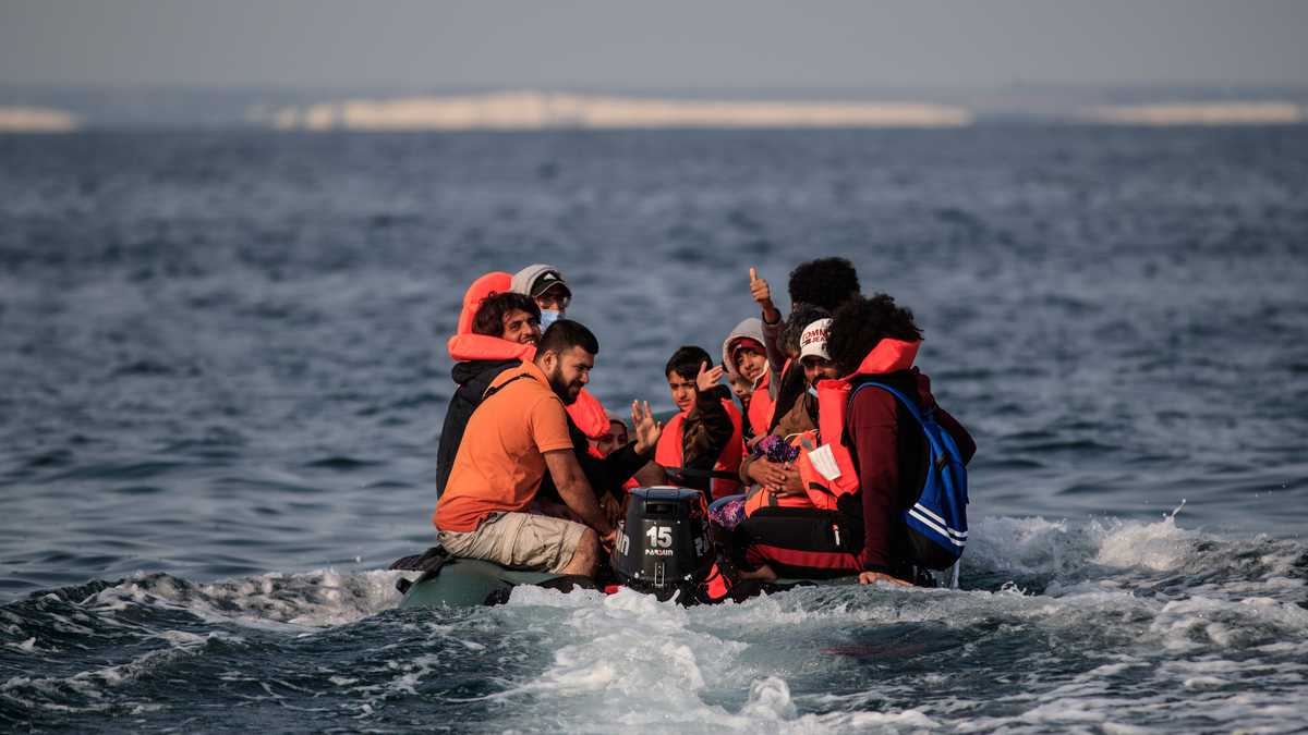 Migrants, including women and children, in a dinghy, react as they approach the southern British coastline as they illegally cross the English Channel from France on September 11, 2020. - The number of migrants crossing the English Channel -- which is 33,8 km (21 miles) at the closest point in the Straits of Dover --  in small inflatable boats has spiralled over the summer of the 2020. According to authorities in northern France some 6,200 migrants have attempted the crossing between January 1 and August 31, 2020, compared with 2,294 migrants for the whole of 2019. (Photo by Sameer Al-DOUMY / AFP)
