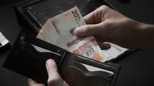 Manos masculinas recogiendo billetes de 20000 pesos colombianos de una billetera en una oficina oscura