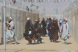 Afghan people walk inside a fenced corridor as they enter Pakistan at the Pakistan-Afghanistan border crossing point in Chaman on August 25, 2021 following the Taliban's stunning military takeover of Afghanistan. (Photo by - / AFP)