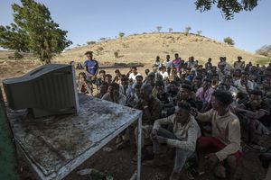 Hombres tigranianos que huyeron del conflicto en la región de Tigray en Etiopía, miran las noticias en una televisor del campo de refugiados de Umm Rakouba en Qadarif, en el este de Sudán, el sábado 5 de diciembre de 2020. Foto: Nariman El-Mofty / AP