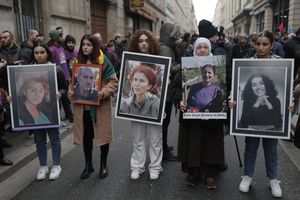 Activistas kurdas con retratos de víctimas en el lugar donde tres mujeres kurdas fueron asesinadas en 2013, en París el 26 de diciembre de 2022.  (Foto AP/Lewis Joly)