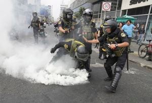 Agentes de policía recogen un bote de gas lacrimógeno que les arrojaron manifestantes antigubernamentales que viajaron a la capital desde todo el país para marchar contra la presidenta peruana Dina Boluarte en Lima, Perú, el miércoles 18 de enero de 2023. (AP Photo/Martin Mejia)