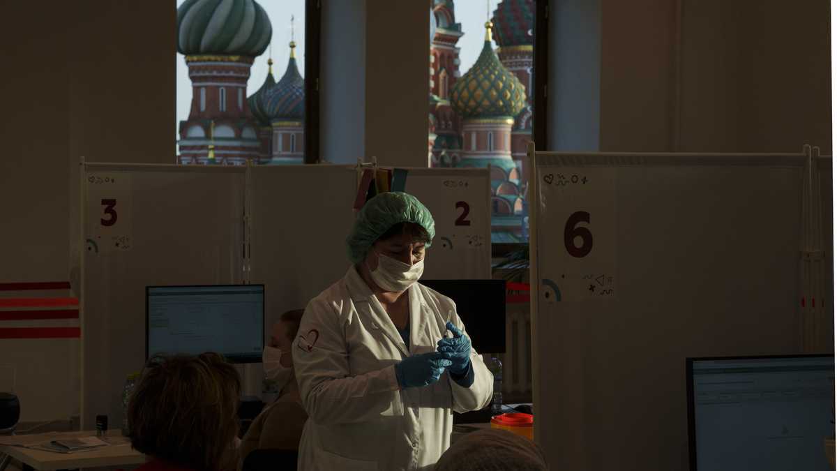 Una trabajadora médica prepara una dosis de la vacuna rusa contra el COVID-19 Sputnik Lite, en un centro de vacunación en una tienda GUM, en la Plaza Roja, con la catedral de San Basilio al fondo, en Moscú, Rusia, el 26 de octubre de 2021. (AP Foto/Pavel Golovkin)
