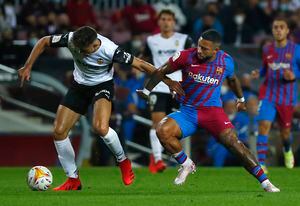 Valencia's Gabriel Paulista, left, challenges for the ball with Barcelona's Memphis Depay during the Spanish La Liga soccer match between FC Barcelona and Valencia at the Camp Nou stadium in Barcelona, Spain, Sunday, Oct. 17, 2021. (AP Photo/Joan Monfort)