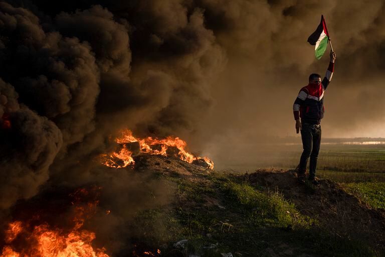 Palestinos queman neumáticos y ondean la bandera nacional durante una protesta contra un operativo militar israelí en Yenín, Cisjordania, el jueves 26 de enero de 2023, en la Ciudad de Gaza. (AP Foto/Fatima Shbair)