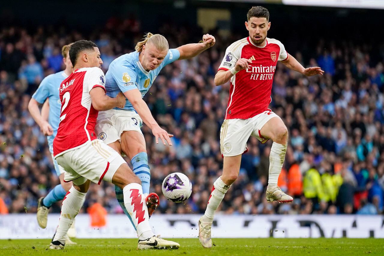 Arsenal's William Saliba, left, tries to block a shot from Manchester City's Erling Haaland during the English Premier League soccer match between Manchester City and Arsenal at the Etihad stadium in Manchester, England, Sunday, March 31, 2024. (AP Photo/Dave Thompson)