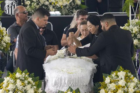 Marcia Aoki, the widow of the late Brazilian soccer great Pele, holds a rosary over his body that lies in state at Vila Belmiro stadium during his wake in Santos, Brazil, Monday, Jan. 2, 2023. (AP Photo/Andre Penner)