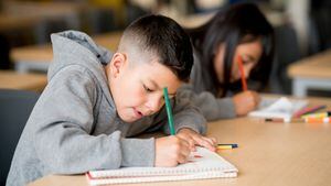 Niños felices estudiando en la escuela y dibujando en sus cuadernos - conceptos educativos