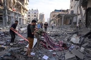 Varios palestinos recogen cadáveres de entre los escombros tras un bombardeo israelí, el miércoles 11 de octubre de 2023, en la Ciudad de Gaza. (AP Foto/Fatima Shbair)