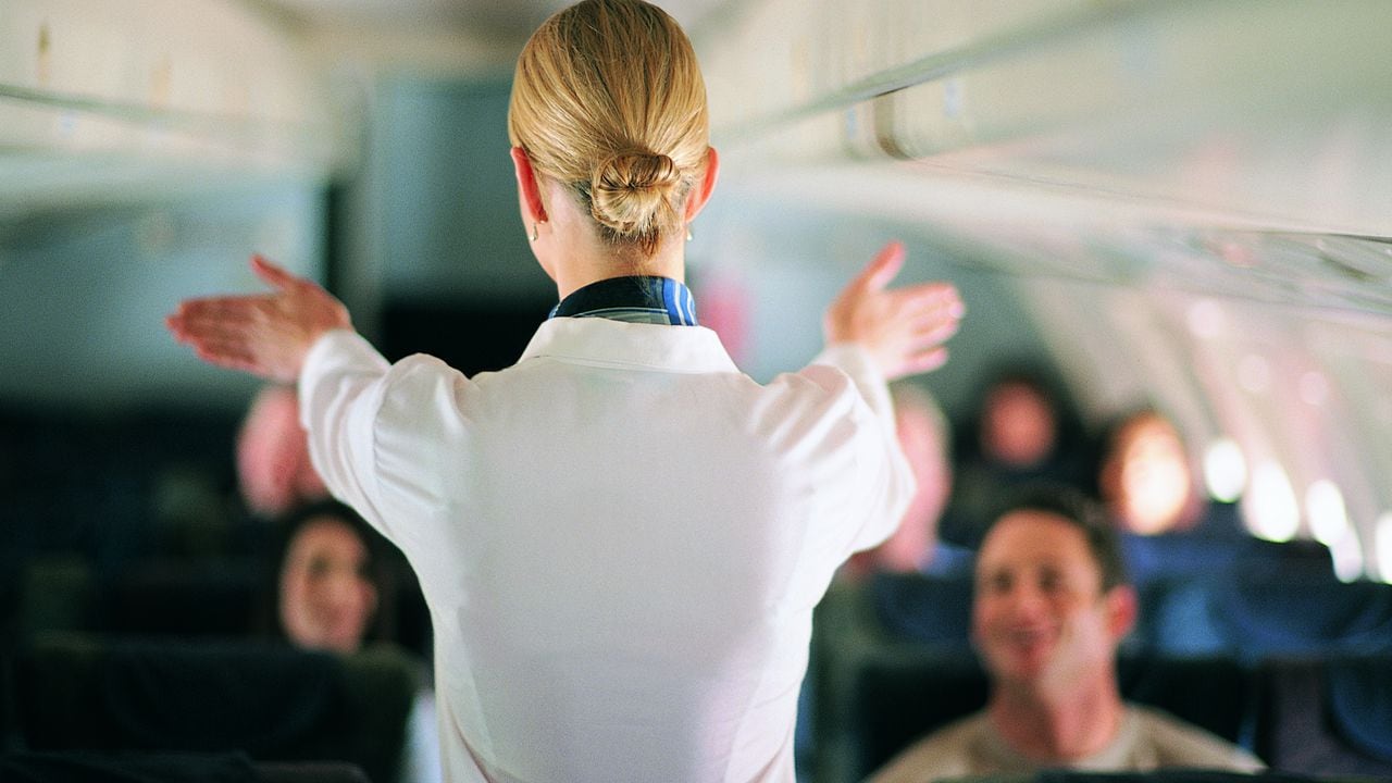 Rear View of Air Stewardess Explaining Aeroplane Safety to Passengers
