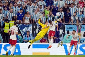 El portero de Polonia Wojciech Szczesny (1) salta por el balón contra Lionel Messi de Argentina y Bartosz Bereszyski de Polonia durante el partido de fútbol del Grupo C de la Copa Mundial entre Polonia y Argentina en el Estadio 974 en Doha, Qatar, miércoles 30 de noviembre de 2022. 