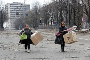 Las mujeres llevan sus pertenencias en una calle destruida durante el conflicto entre Ucrania y Rusia en la ciudad portuaria sureña de Mariupol, Ucrania, el 14 de abril de 2022. Foto REUTERS/Alexander Ermochenko