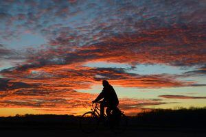 Un hombre maneja en bicicleta durante una puesta de sol en Friburgo, Alemania. (AP)