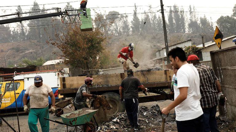 Los residentes locales retiran los restos de las casas quemadas después de un incendio forestal en Purén, cerca de Temuco, Chile.