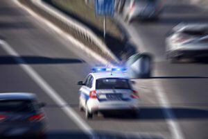 Police car with blue lights moving fast in traffic urban environment.