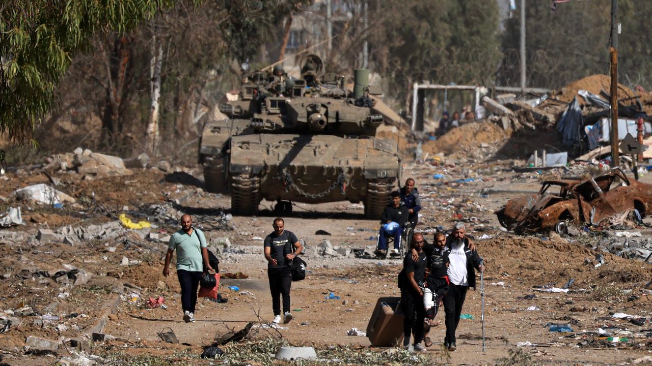 Palestinos que huyen del norte por la carretera de Salaheddine pasan junto a un tanque del ejército israelí en el distrito de Zeitoun, en las afueras del sur de la ciudad de Gaza, el 24 de noviembre de 2023, tras un alto el fuego de cuatro días que comenzó a primera hora de la mañana.
