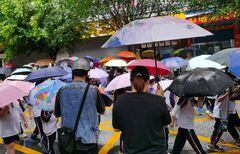 Los padres sostienen paraguas para recoger a los estudiantes en la puerta de la escuela mientras las clases de jardín de infantes se reanudan al mediodía en Qingyuan, provincia de Guangdong, en el sur de China, el 23 de abril de 202
